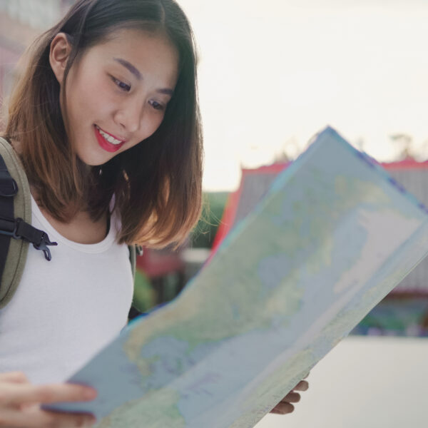 Cheerful beautiful young Asian backpacker woman direction and looking on location map while traveling at Chinatown in Beijing, China. Lifestyle backpack tourist travel holiday concept.