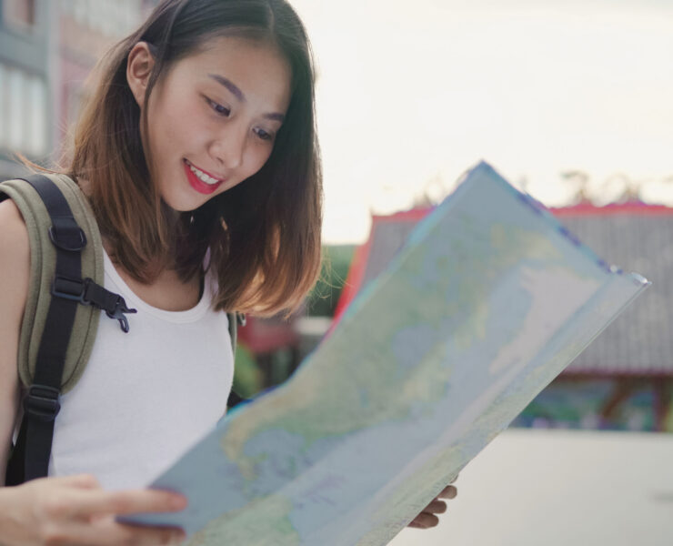 Cheerful beautiful young Asian backpacker woman direction and looking on location map while traveling at Chinatown in Beijing, China. Lifestyle backpack tourist travel holiday concept.