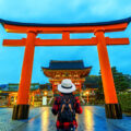 Woman traveler with backpack at fushimi inari taisha shrine in Kyoto, Japan.