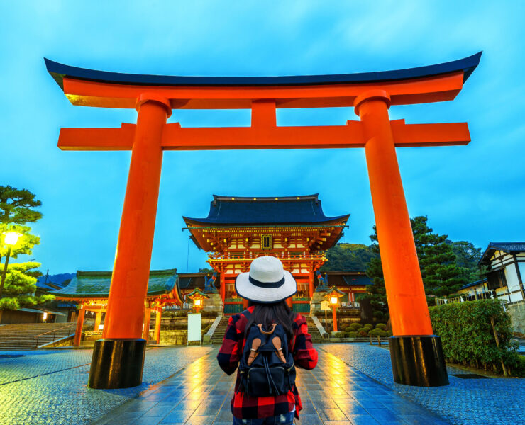 Woman traveler with backpack at fushimi inari taisha shrine in Kyoto, Japan.